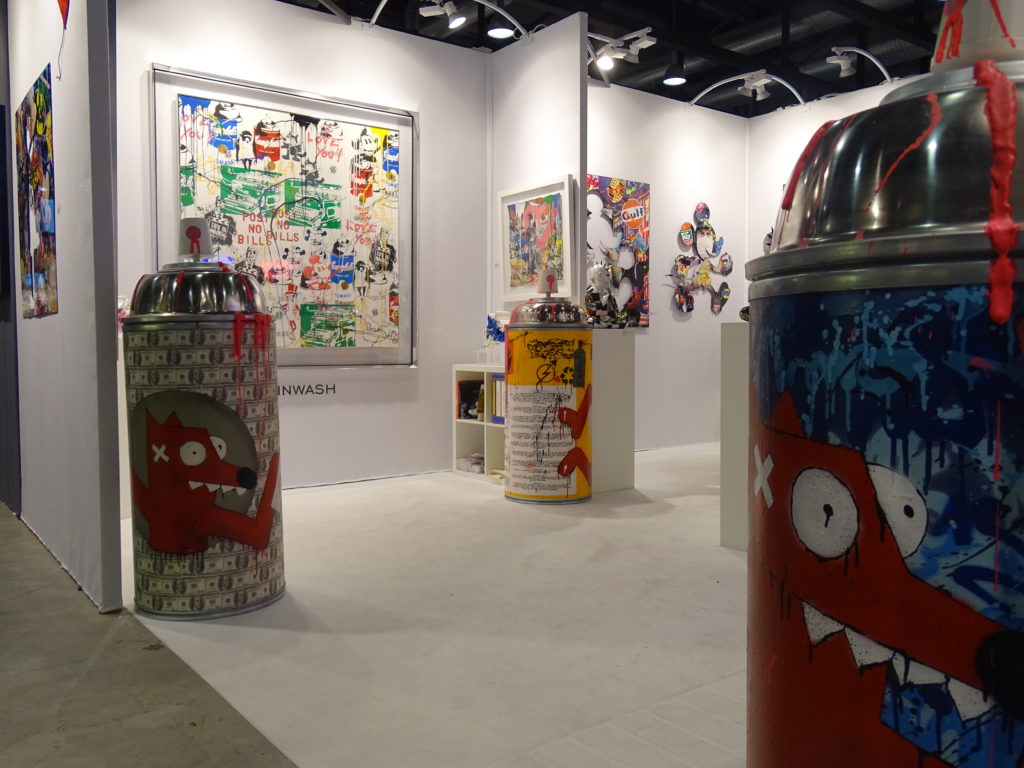 Aperçu du stand de la galerie BELAIR FINEARTau sein du Lausanne ArtFair. On aperçoit des bombes de peintures géantes, l'outil de base du Street-art réalisées par PIMAX et divers tableaux aux couleurs très vives.